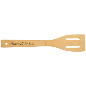 Wooden cooking spatula with a name wood burned on the handle.