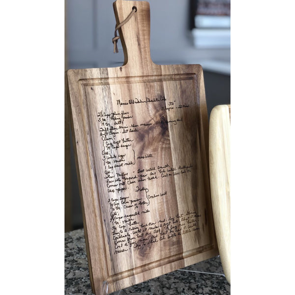 Acacia wood cutting board with handle custom engraved with a hand written recipe.