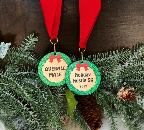 Wood medallions printed with a colorful red and green wreath attached to a red neck ribbon.