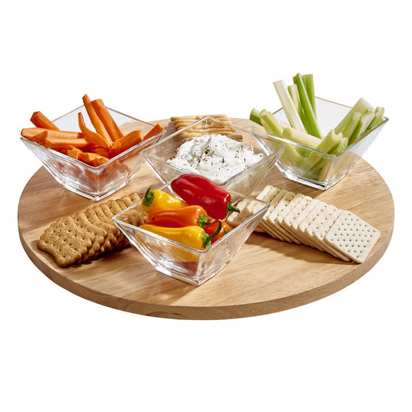 Large round lazy susan cutting board displaying crackers, carrots, celery, and dip.