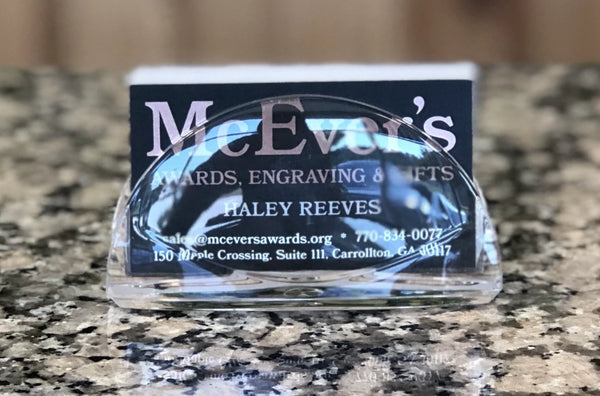 Clear acrylic semi circle shaped business card holder for table top. Holding a stack of black business cards.
