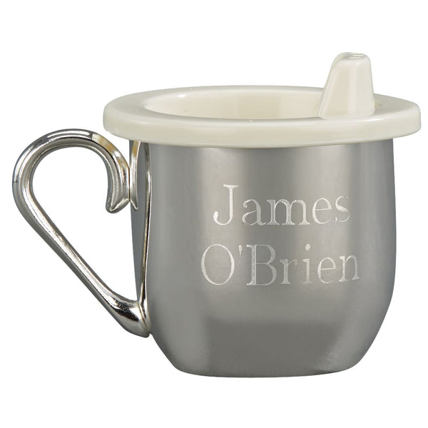 Silver metal baby sippy cup with a handle and plastic lid engraved with a name.