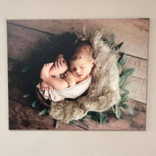 Custom photo canvas print of a newborn baby wrapped up in a floral basket.