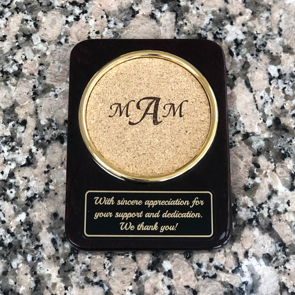 High gloss rosewood rectangular shaped coaster with round cork area to sit your drink. Cork is engraved with a  monogram. below the round cork coaster is a black and gold engraved plate with a special message.