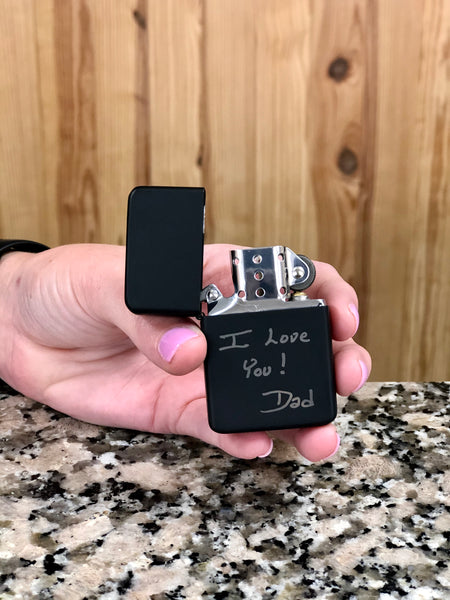 Matte black lighter engraved with custom handwriting on the bottom half.