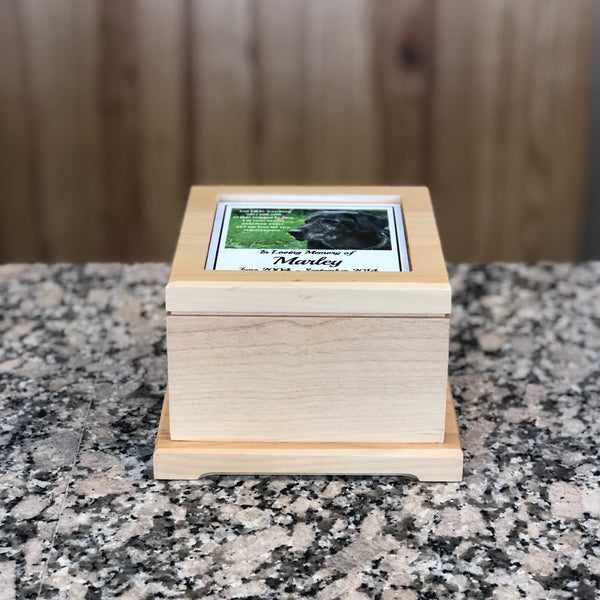Wooden pet urn with colorful picture plate of a dog on top. Plate features a quote, name, and birth and death date.