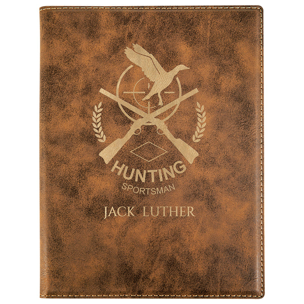 Small brown leatherette portfolio. The front of the portfolio is engraved with a gold company logo in the center. The portfolio opens up to reveal a lined white note pad.