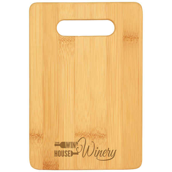 Small rectangle cutting board with cut out handle featuring a winery's custom logo engraved at the bottom center.
