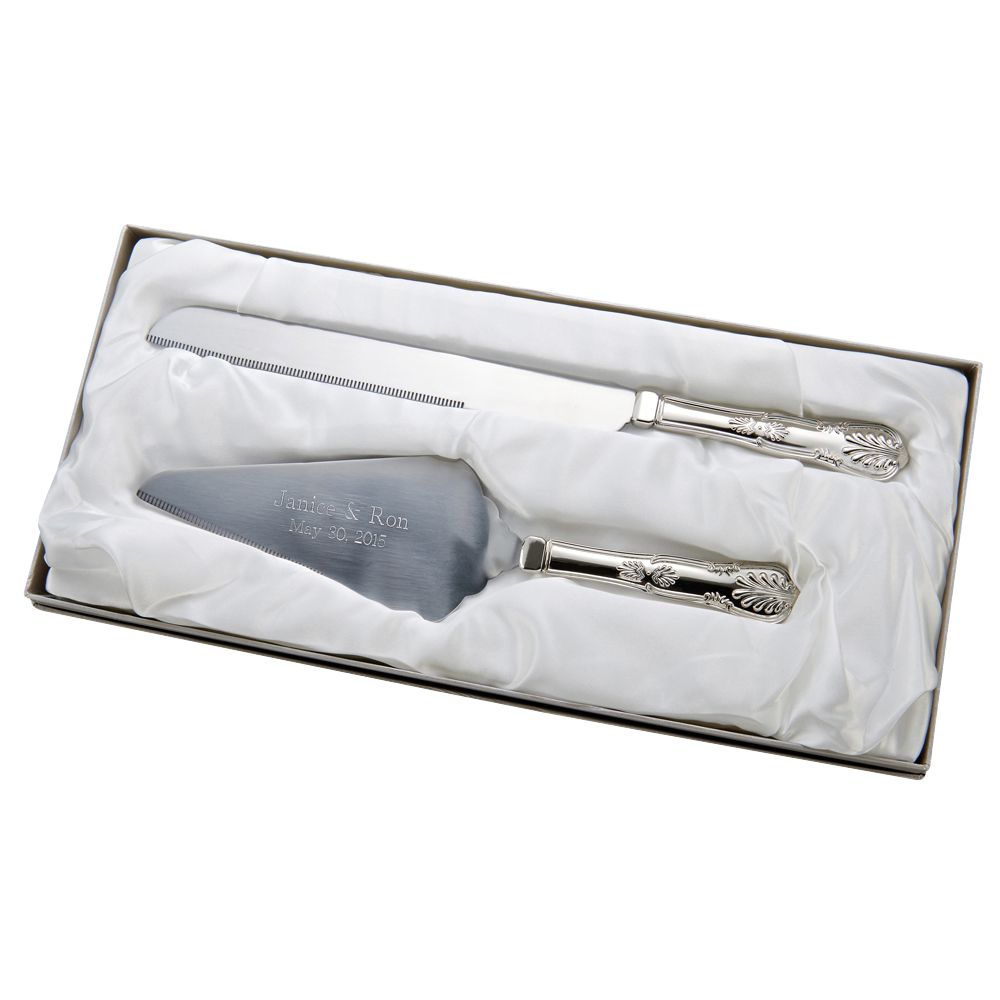 Shiny silver metal cake server and knife set featuring an ornate design on the handles and engraved with a two names and a wedding date on the cake server.