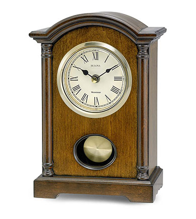 Rectangle shaped walnut clock with pendulem and curved top. Features a white face with black roman numerals. Clock face is outlined in gold.