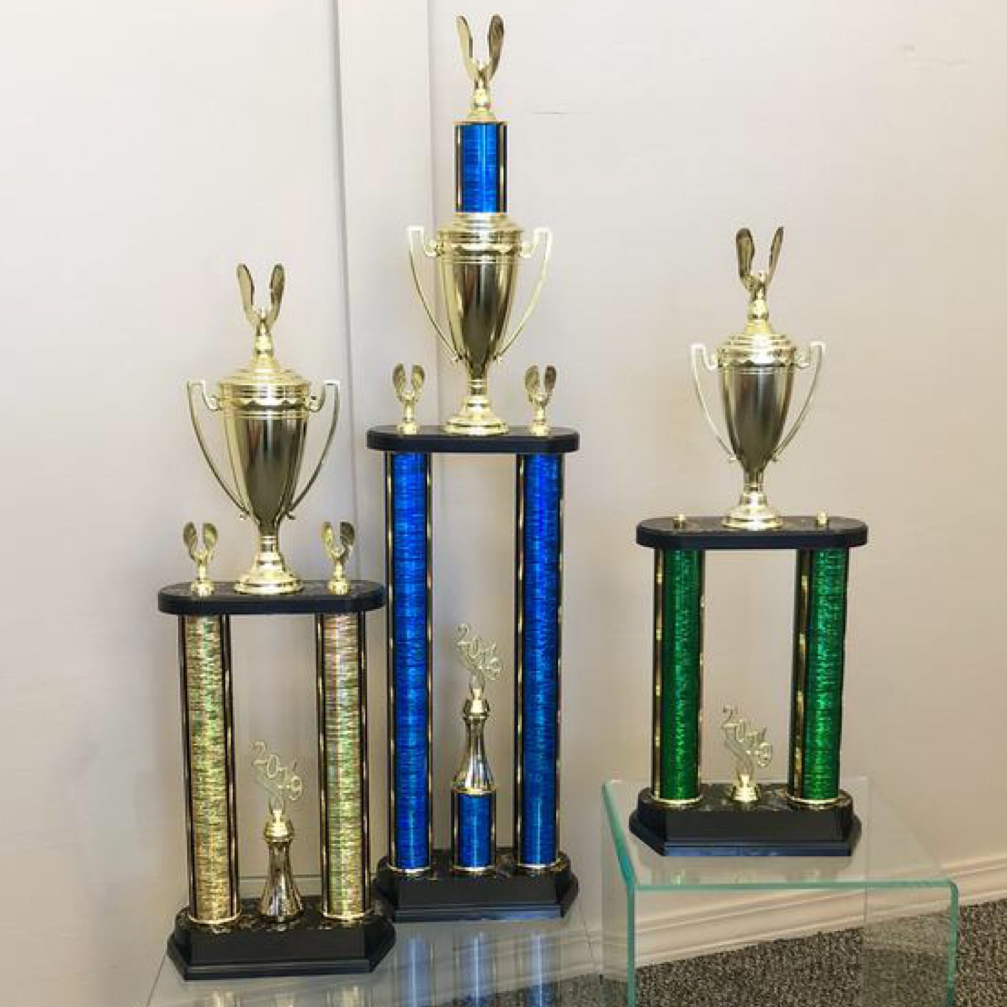 Medium size two post column trophies. Gold two post trophy with cup. Blue two post column trophy with cup. Green two post column trophy with cup.