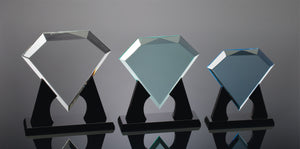 Left: Large clear diamond shaped acrylic award sitting on a black base. Center: Medium jade colored diamond shaped acrylic award on black base. Right: Small blue diamond shaped acrylic award on a black base.