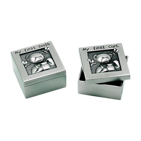 Two small square silver boxes with lids that feature a teddy bear. On the lid of each box reads "My First Tooth" or "My First Curl" in black letters. A name is engraved on the side of each of the boxes.