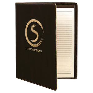 Large black leatherette portfolio. The front of the portfolio is engraved with a gold company logo to match gold stitching around the edges. The portfolio opens up to reveal a lined white note pad.