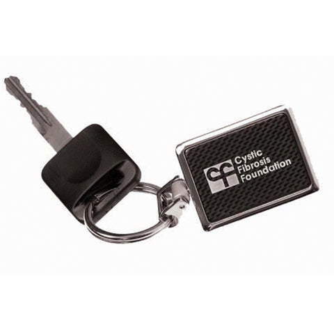 Rectangle shaped keychain with a shiny silver border, back, and key ring. The front of the keychain is black and dark grey checkered. It is engraved with a frosty white colored logo.