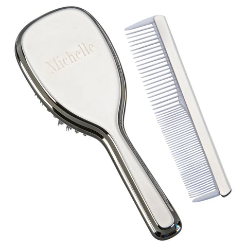 Engraved shiny silver baby brush with handle and baby comb with white teeth.