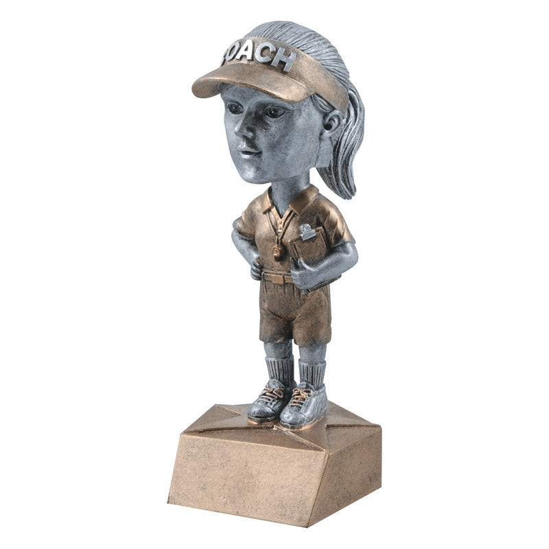 Female coach bobble head trophy featuring a gold base, gold outfit, and silver coach's head with a ponytail. Coach has on a gold visor that reads "COACH" in silver letters.