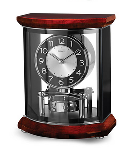 Large clock featuring a solid hardwood top and base, high-gloss piano finish over mahogany stain with a clear acrylic front and back. Sides are matte black. Polished chrome inlaid accents, bun feet and revolving pendulum. Black and silver clock face.
