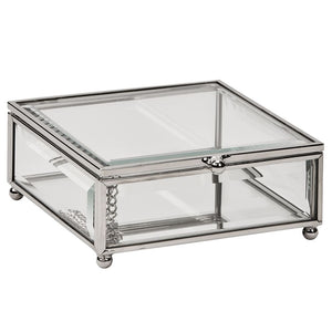 Rectangle shaped glass jewelry box with silver edges and corners and round feet.