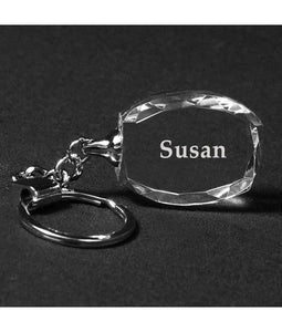Oval faceted clear crystal keychain with silver chain and key ring. The crystal keychain is engraved with a name in a frosty white color.