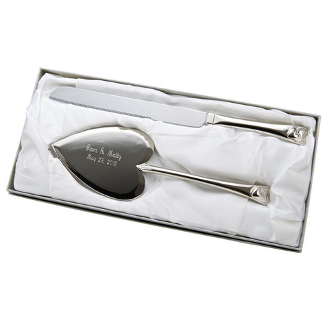 Shiny silver metal cake server and knife set featuring a heart shaped cake server engraved with two names and a wedding date. The bottom of the handles feature two hearts intertwined. 