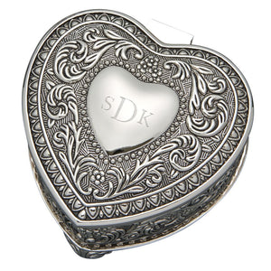 Heart shaped hinged jewelry box with an ornate paisley and floral design on the top and sides. Top features small flat heart shape in center that is engraved with a monogram.