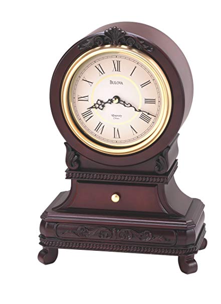Large Bulova Knollwood clock featuring four feet, an ornate design on the bottom half of the clock, and a large round cream colored clock face with black hands and roman numerals.