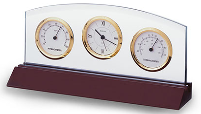 Cherry wood colored long base that has a skinny clear glass piece attached and houses a clock, thermometer, and hygrometer all outlined in shiny gold with white faces and black hands and numbers.