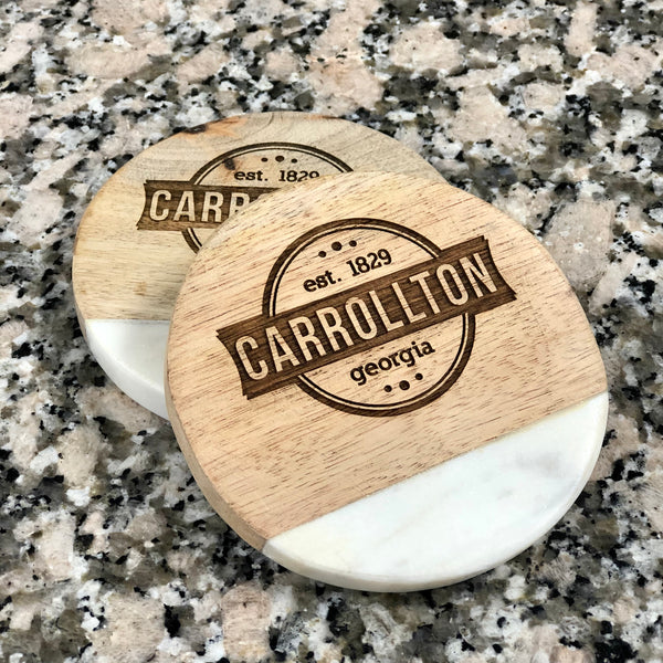 Set of four wood and marble engraved coasters. Coasters are 3/4 wood and 1/4 marble. Marble slab is at the bottom of each coaster. Coasters are engraved with a city of Carrollton logo.